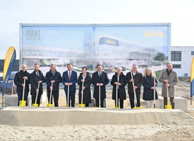 Gruppenfoto Pauat Architekten vor einem Plakat mit Schaufeln in der Hand